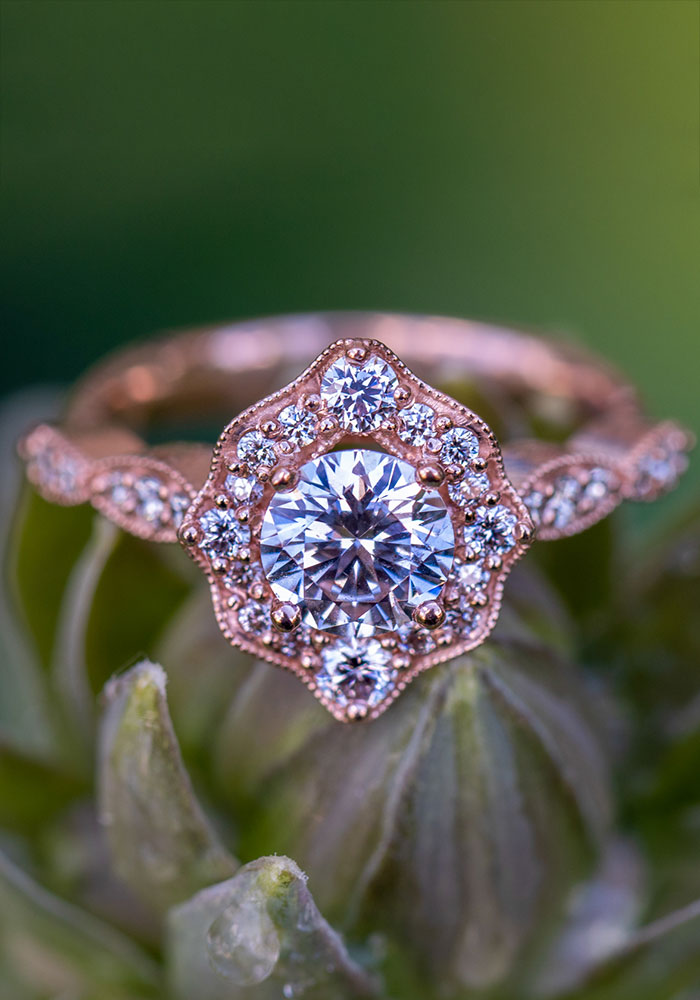 a diamond ring with a halo of diamonds sits on a plant