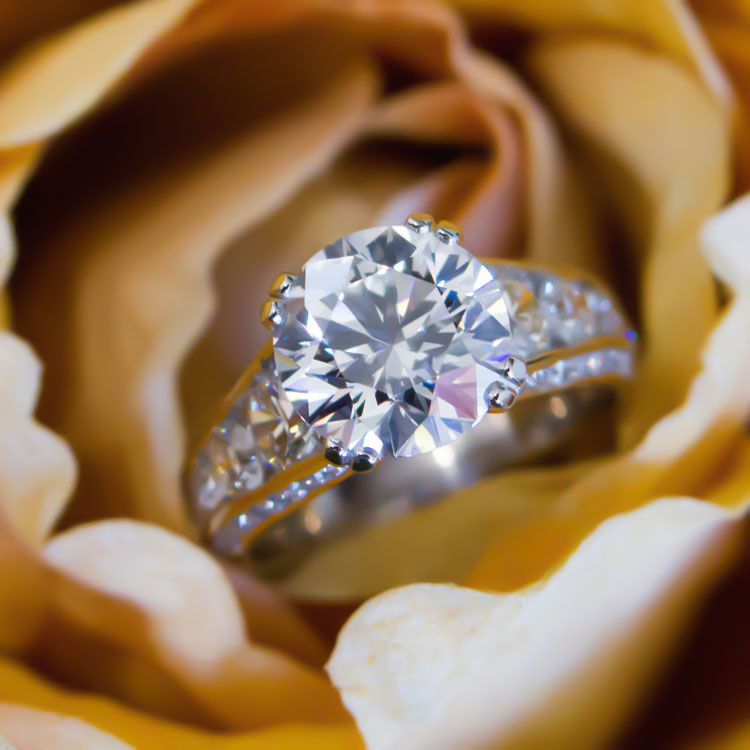 A handcrafted ring with large diamond lays on an orange background